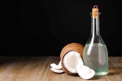 Photo of Coconut oil on wooden table against black background. Space for text