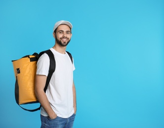 Photo of Young courier with thermo bag on color background, space for text. Food delivery service