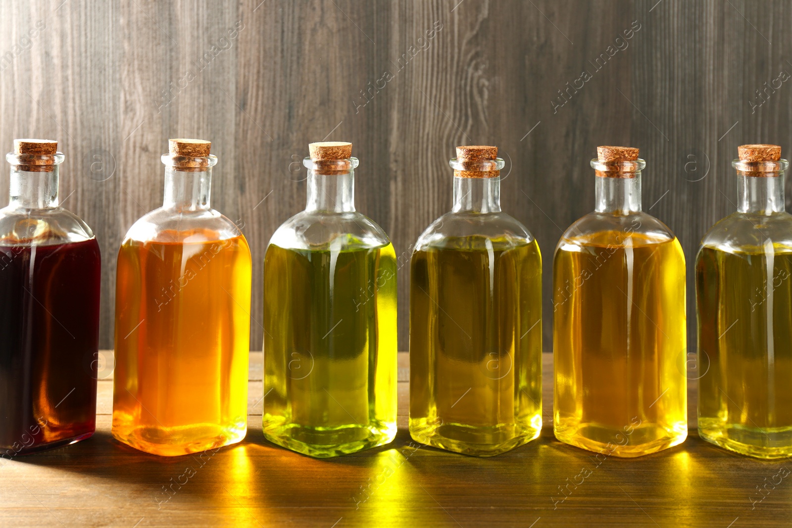 Photo of Vegetable fats. Different oils in glass bottles on wooden table