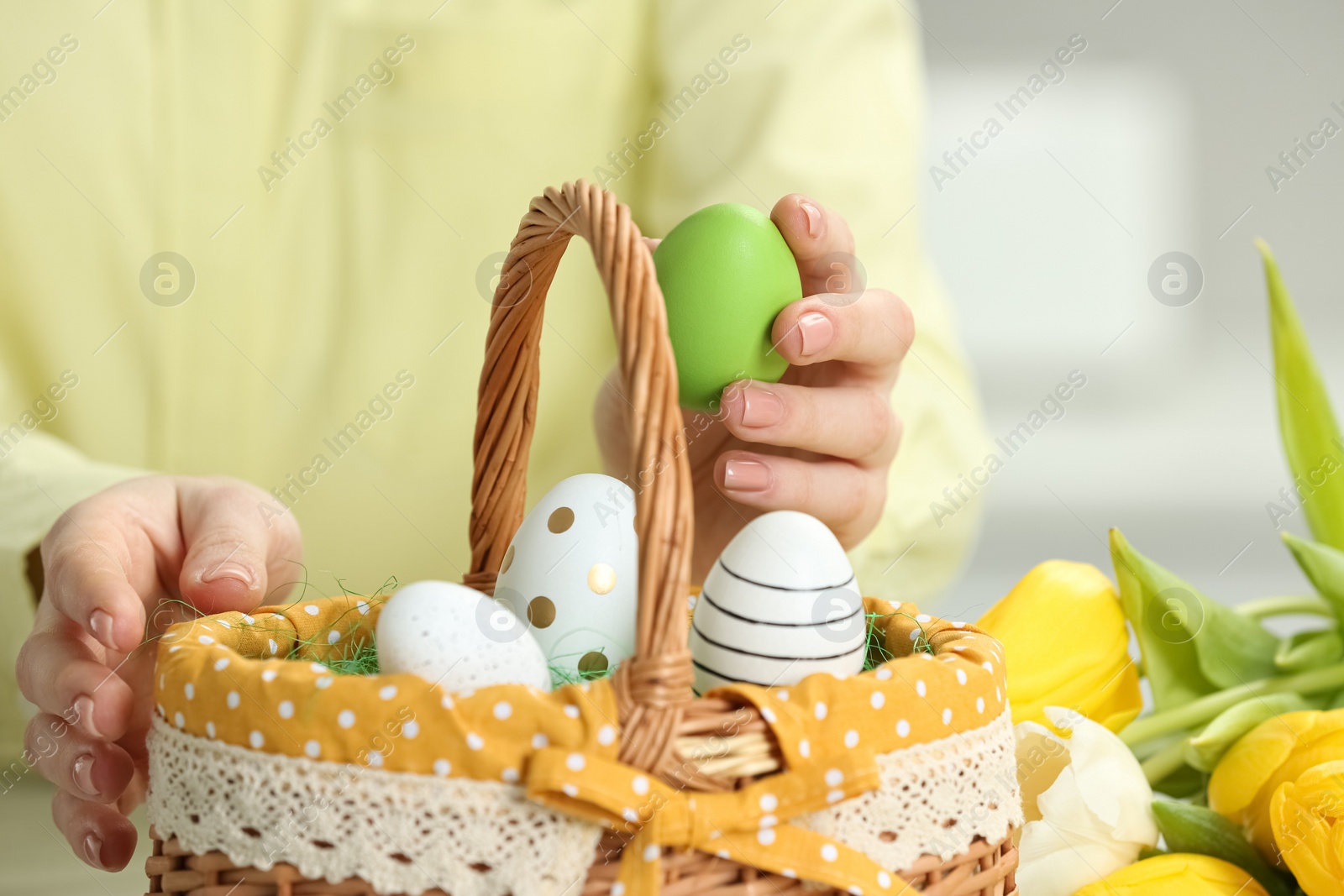 Photo of Closeup of woman putting painted egg into Easter basket