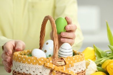 Photo of Closeup of woman putting painted egg into Easter basket