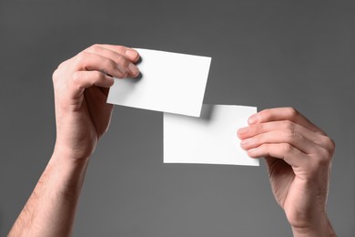 Photo of Man holding paper cards on grey background, closeup. Mockup for design