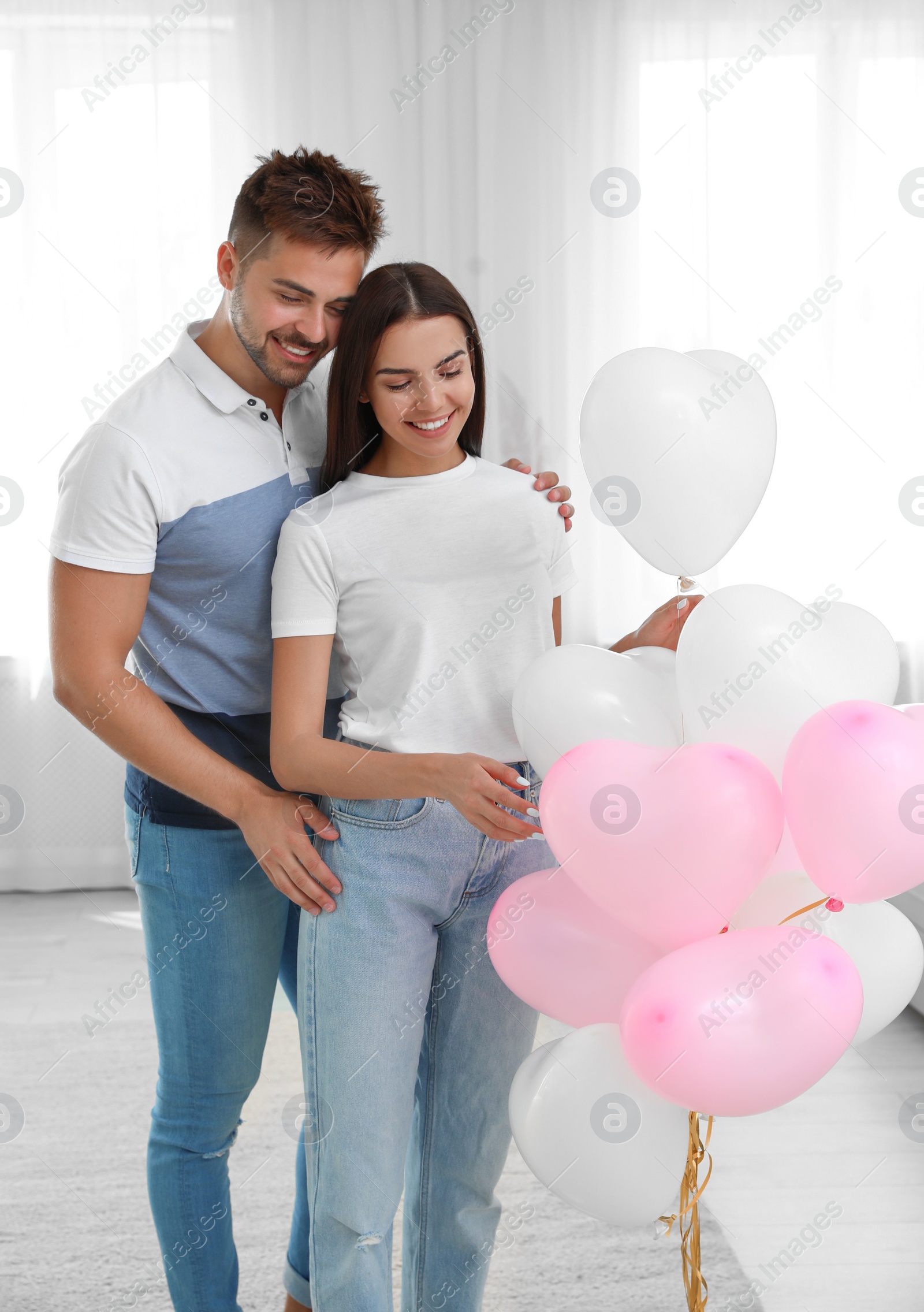 Photo of Young couple with air balloons at home. Celebration of Saint Valentine's Day