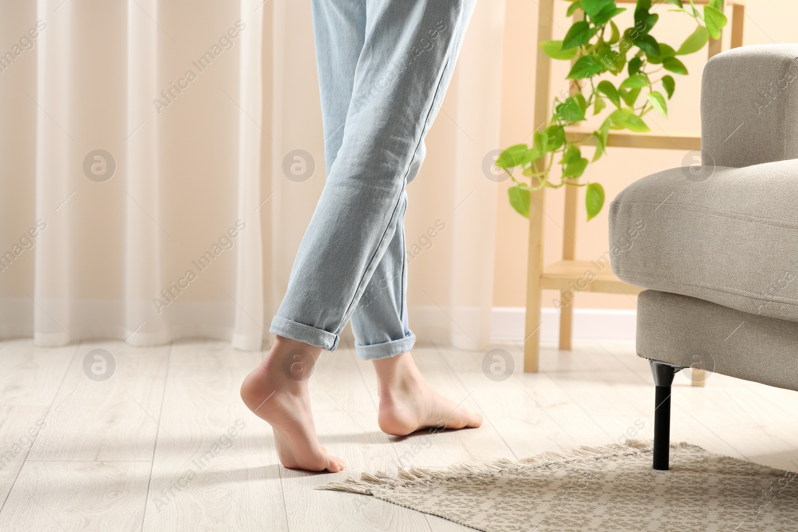 Photo of Woman stepping barefoot in room at home, closeup. Floor heating