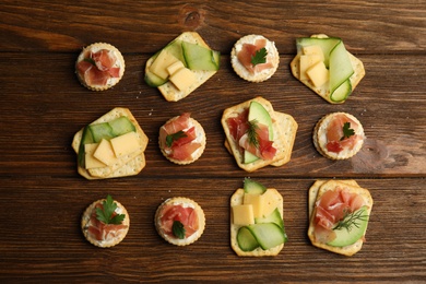 Different snacks with salted crackers on wooden table, flat lay