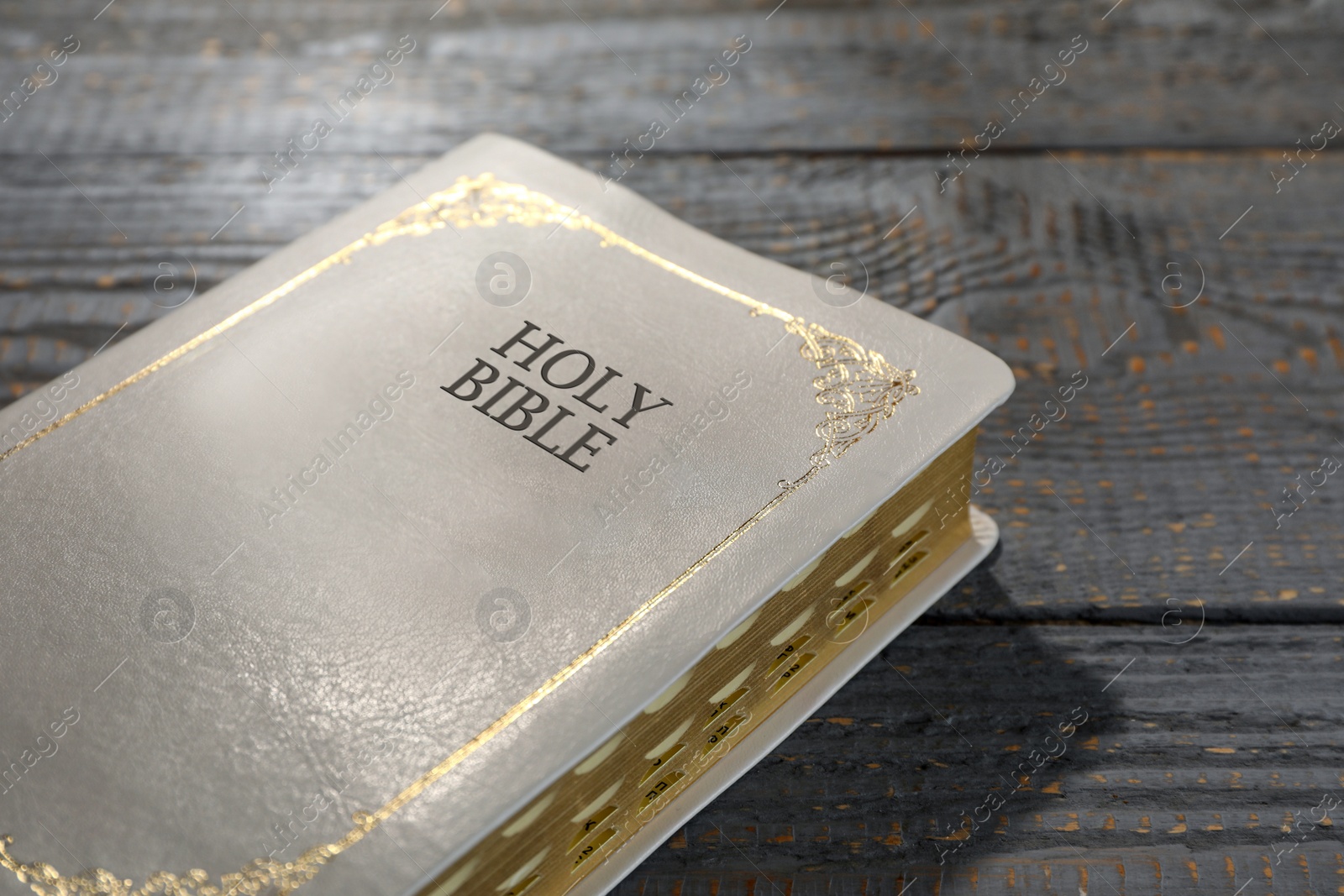 Photo of Old hardcover Bible on grey wooden table, closeup. Religious book