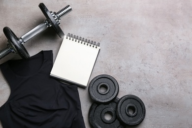 Photo of Flat lay composition with sportswear, notebook and equipment on grey background, space for text. Gym workout plan
