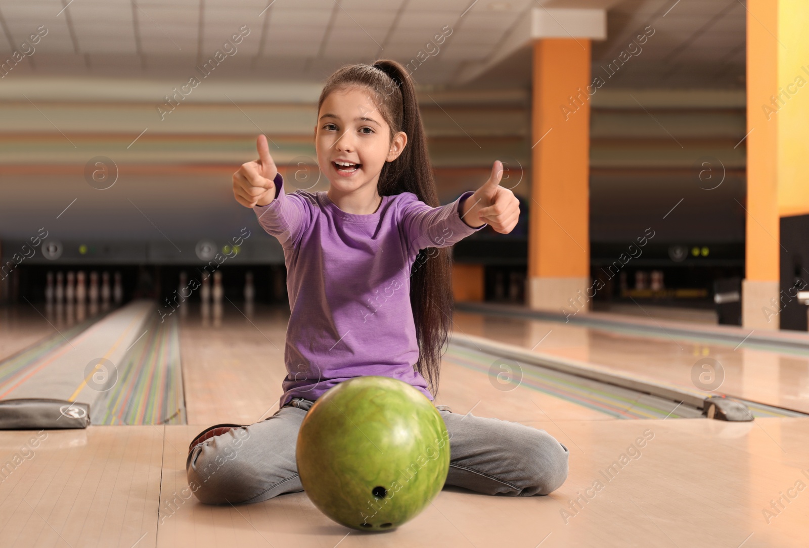 Photo of Little girl with ball in bowling club