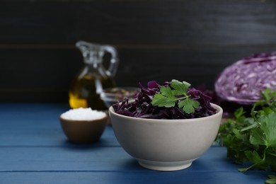 Tasty red cabbage sauerkraut with parsley on light blue wooden table. Space for text