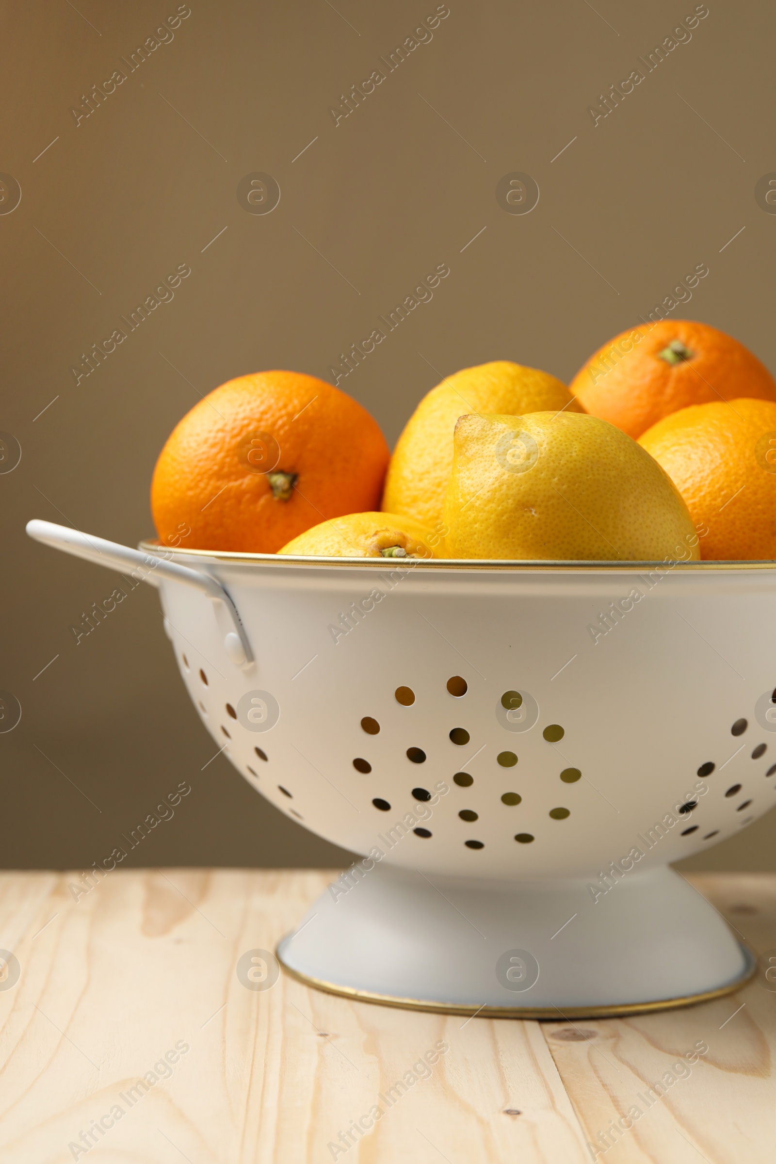 Photo of Colander with fresh citrus fruits on wooden table, closeup