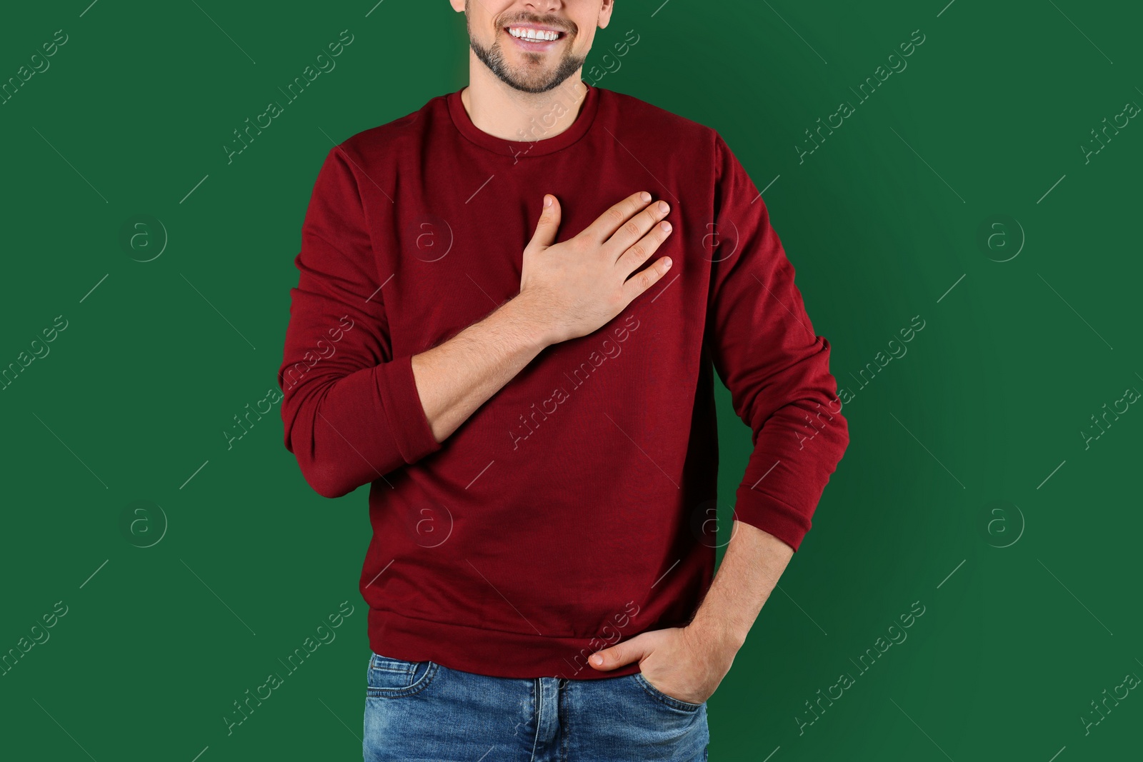 Photo of Man holding hand near his heart on color background, closeup