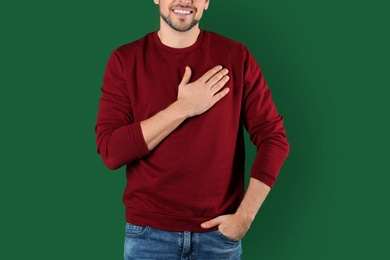 Photo of Man holding hand near his heart on color background, closeup