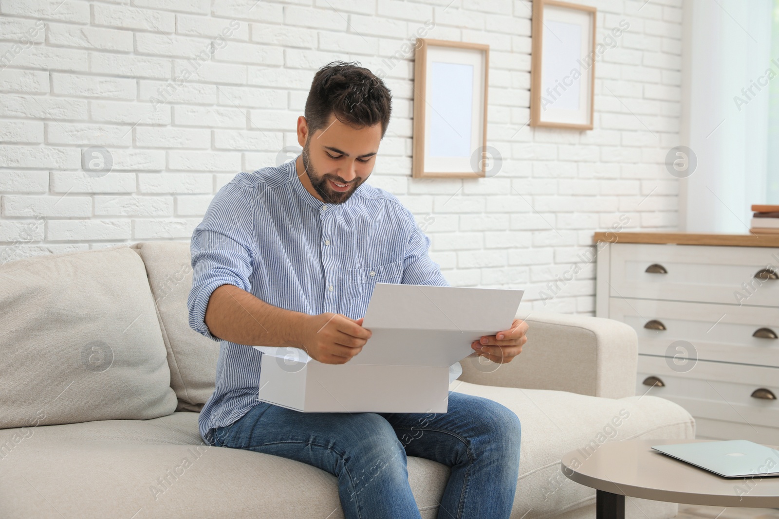 Photo of Man unpacking parcel at home. Online shopping