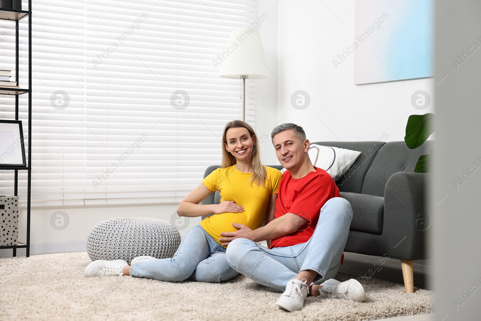 Photo of Young family housing concept. Pregnant woman with her husband on floor at home