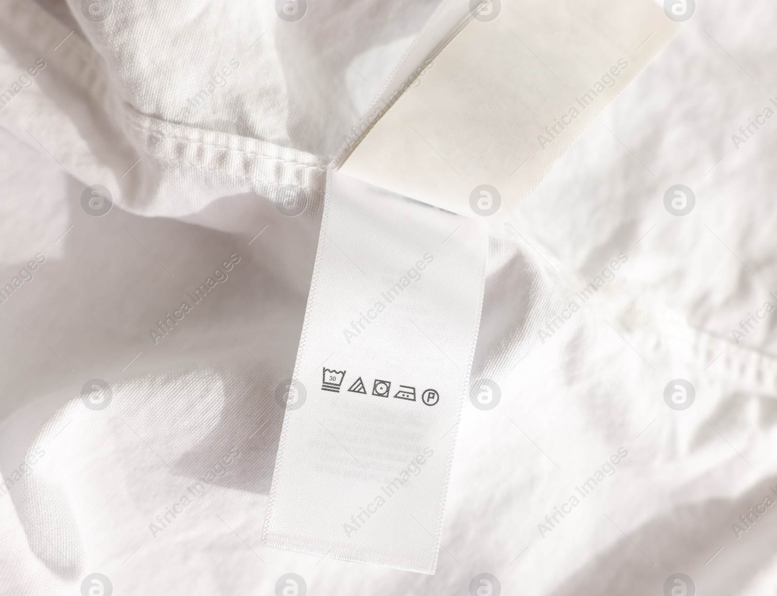 Photo of Clothing label in Chinese language on white garment, closeup