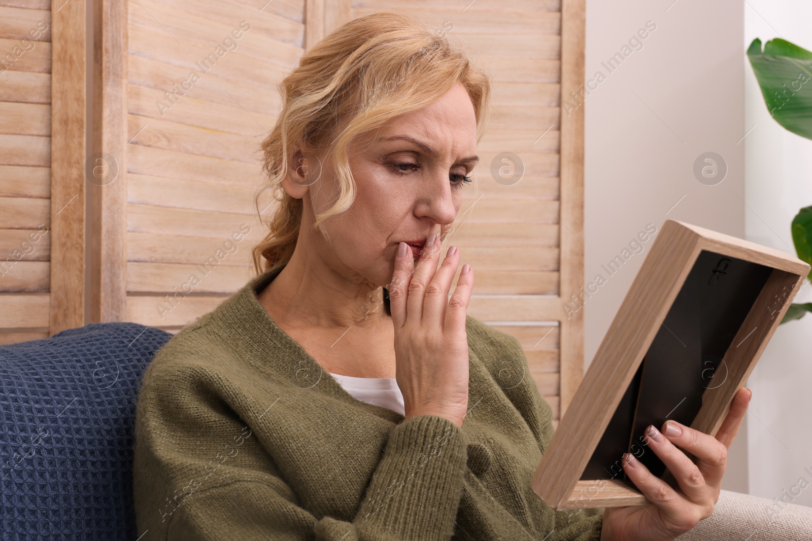 Photo of Upset middle aged woman with photo frame at home. Loneliness concept