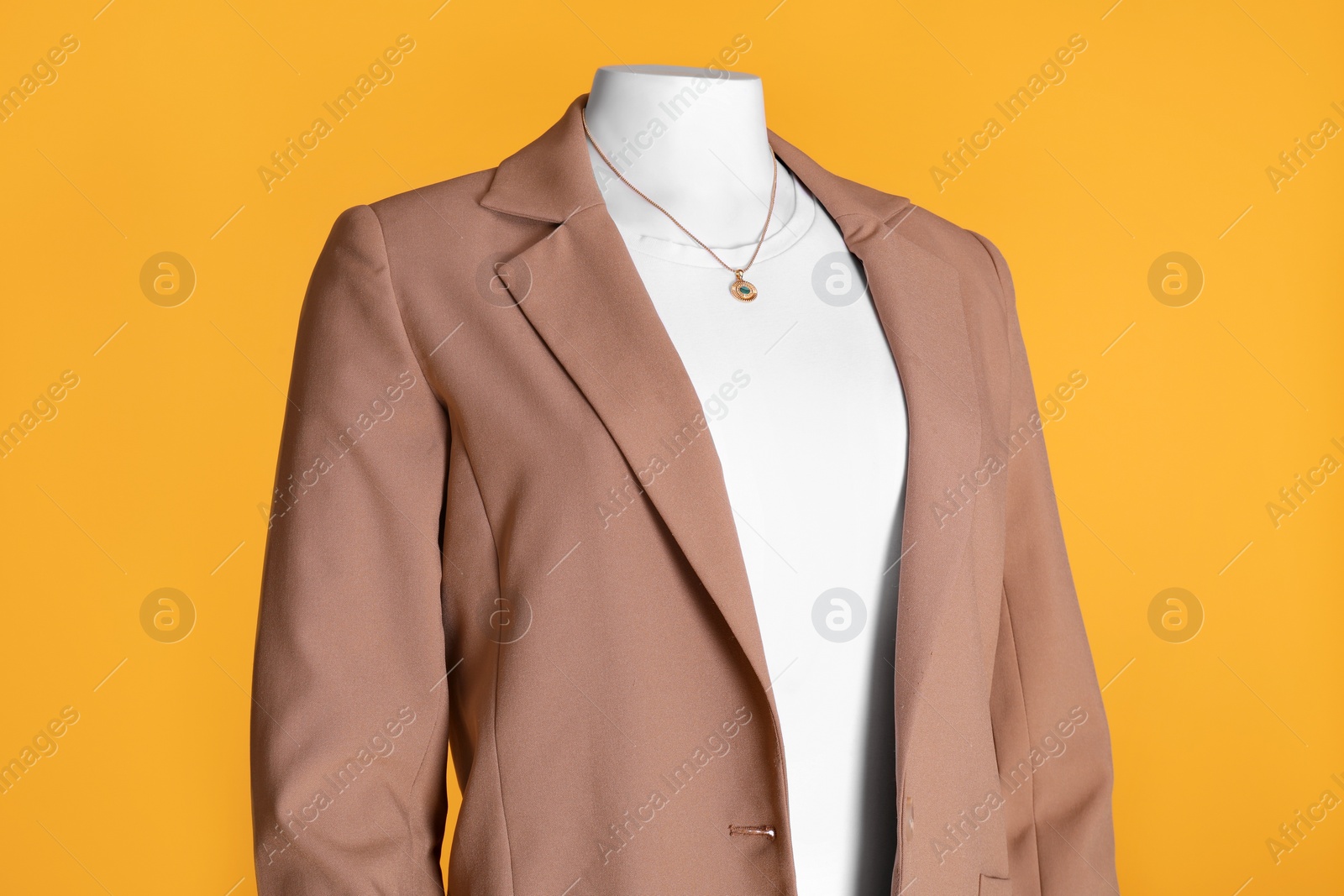 Photo of Female mannequin dressed in white t-shirt with necklace and stylish jacket on orange background