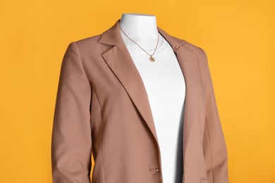Photo of Female mannequin dressed in white t-shirt with necklace and stylish jacket on orange background