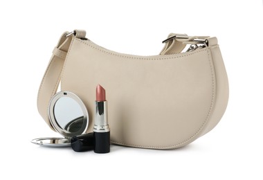 Stylish baguette bag with pocket mirror and lipstick isolated on white