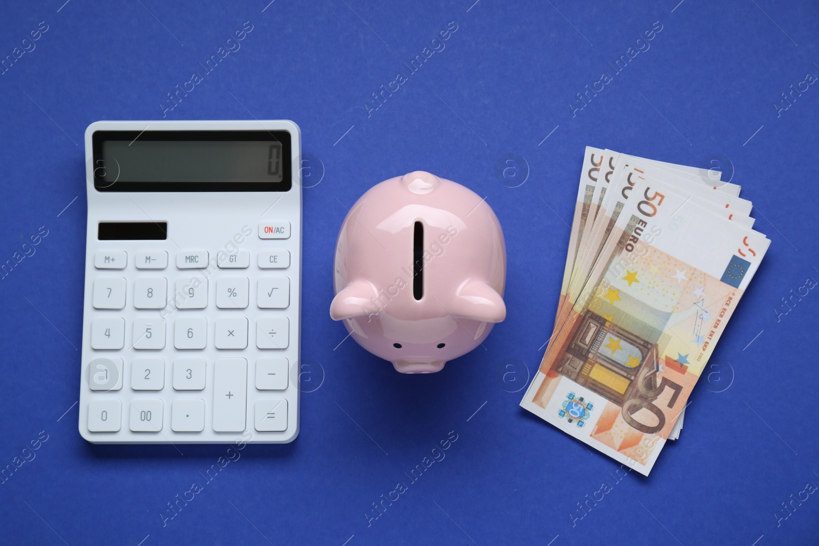 Photo of Piggy bank, calculator and banknotes on blue background, flat lay