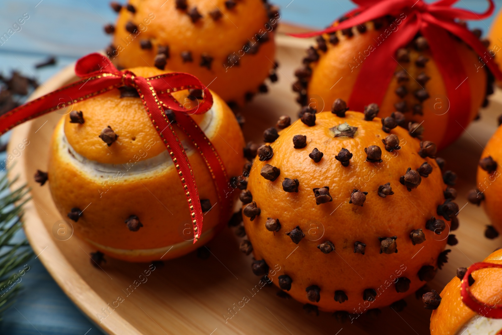 Photo of Pomander balls made of tangerines with cloves and fir branch on wooden table, closeup