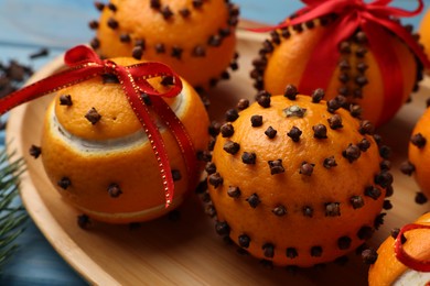 Pomander balls made of tangerines with cloves and fir branch on wooden table, closeup