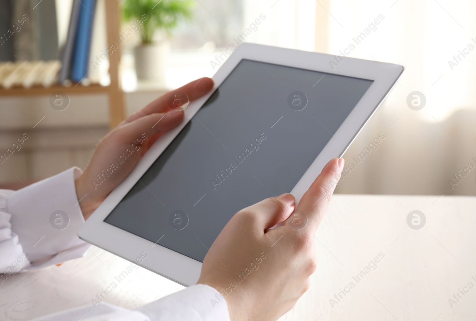 Photo of Woman with modern tablet at table indoors, closeup