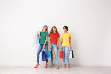 Photo of Group of young women with shopping bags near light wall