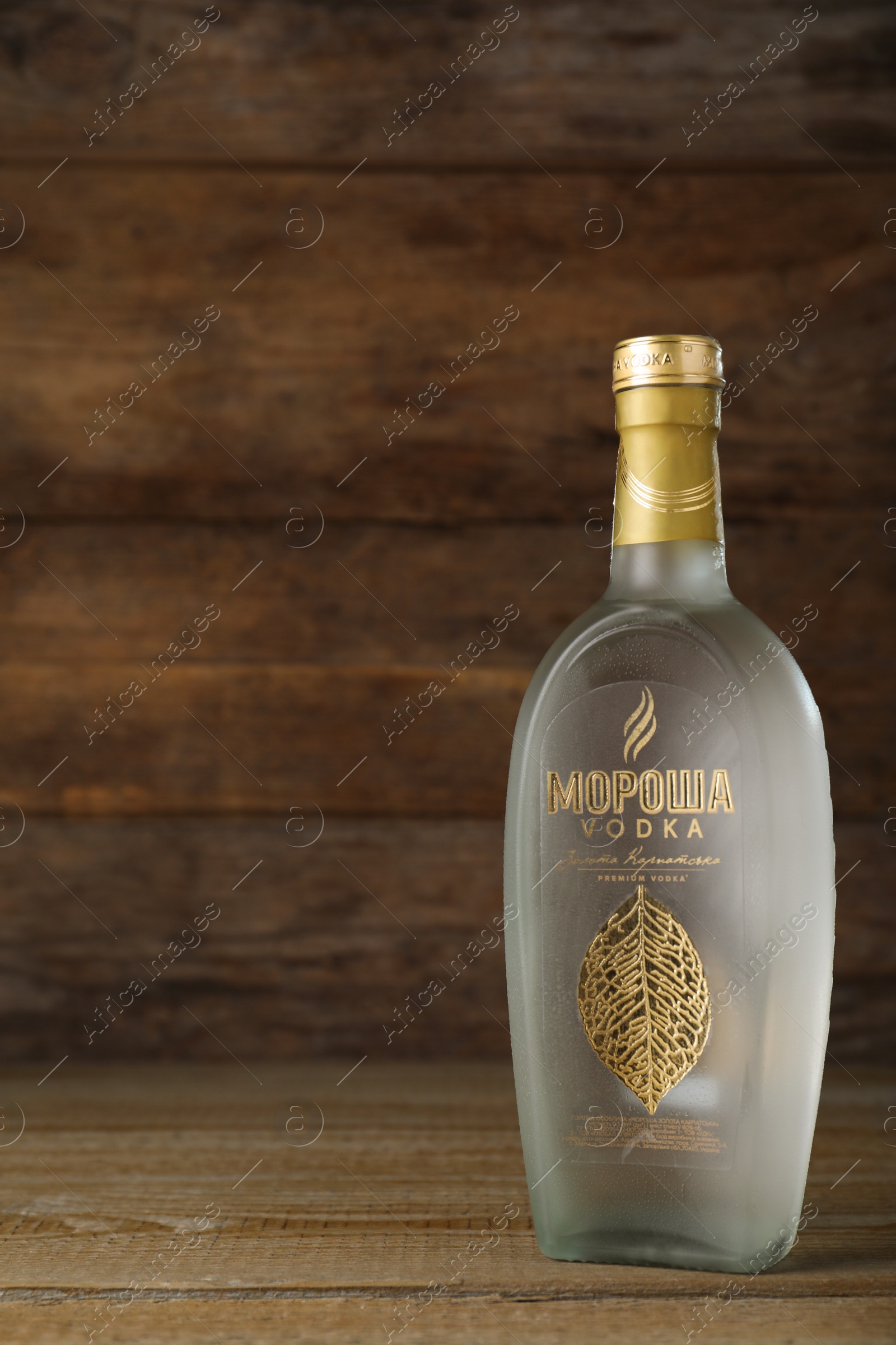 Photo of MYKOLAIV, UKRAINE - OCTOBER 03, 2019: Bottle of Morosha vodka on table against wooden background. Space for text