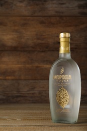 Photo of MYKOLAIV, UKRAINE - OCTOBER 03, 2019: Bottle of Morosha vodka on table against wooden background. Space for text