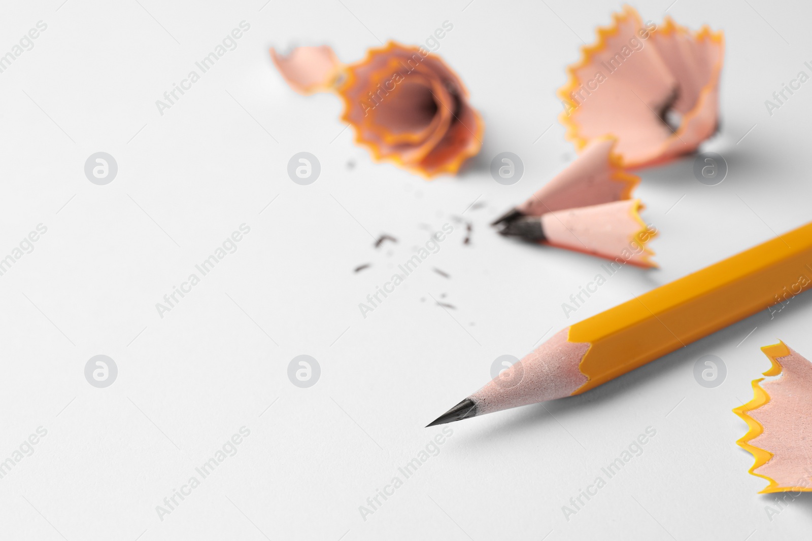 Photo of Graphite pencil and shavings on white background, closeup. Space for text