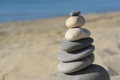 Photo of Stack of stones on sandy beach, closeup. Space for text