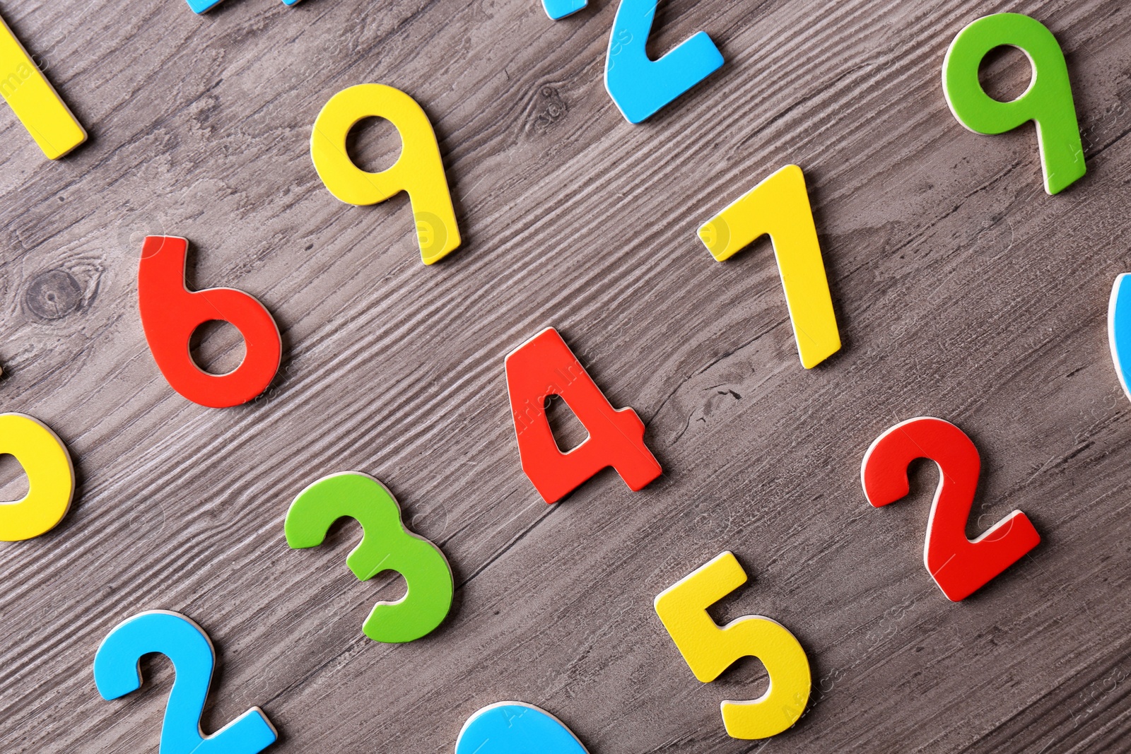 Photo of Colorful numbers on wooden school desk, flat lay