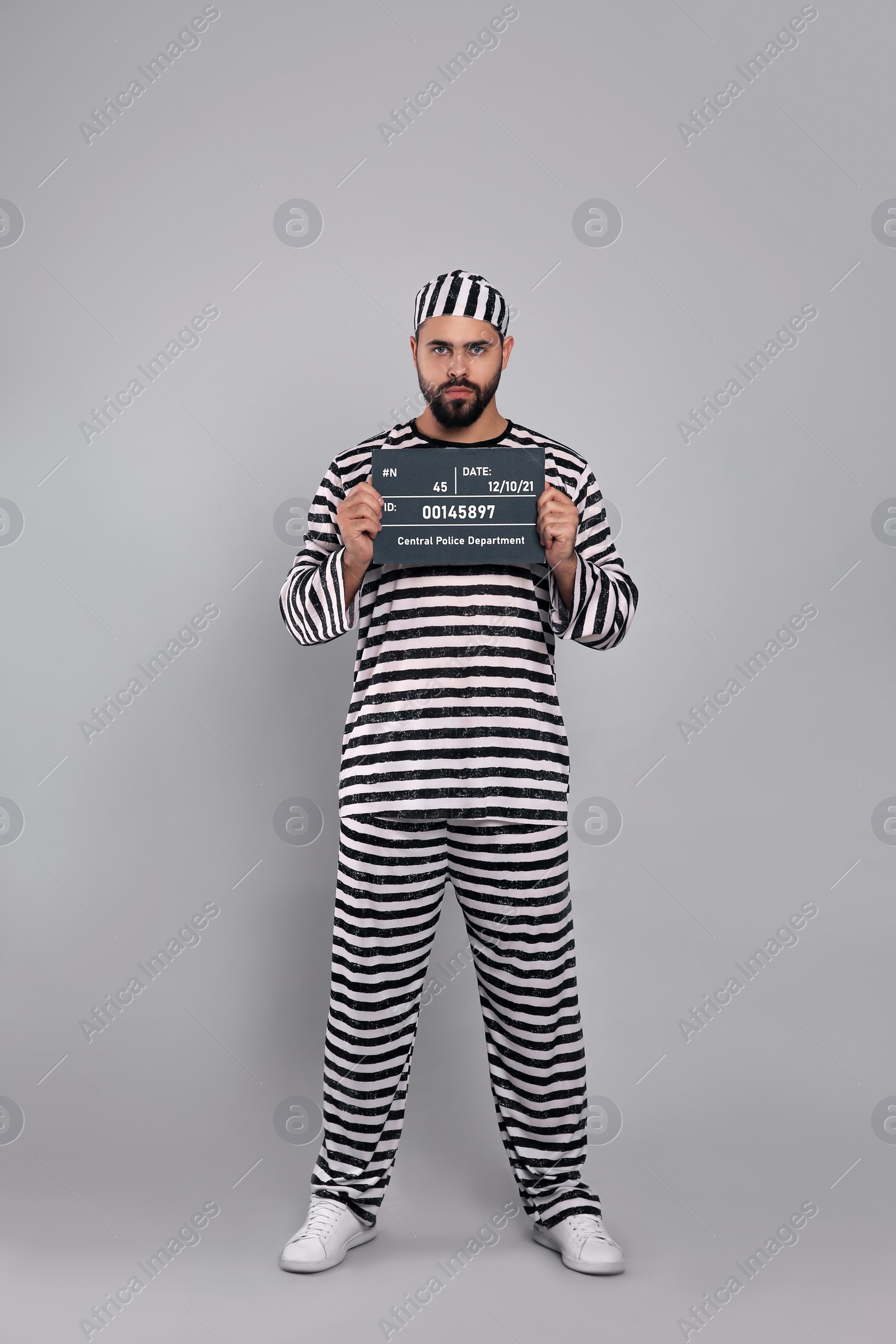 Photo of Prisoner in special uniform with mugshot letter board  
on grey background