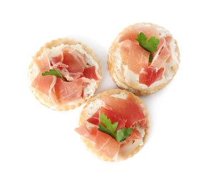 Photo of Delicious crackers with cream cheese, prosciutto and parsley on white background, top view