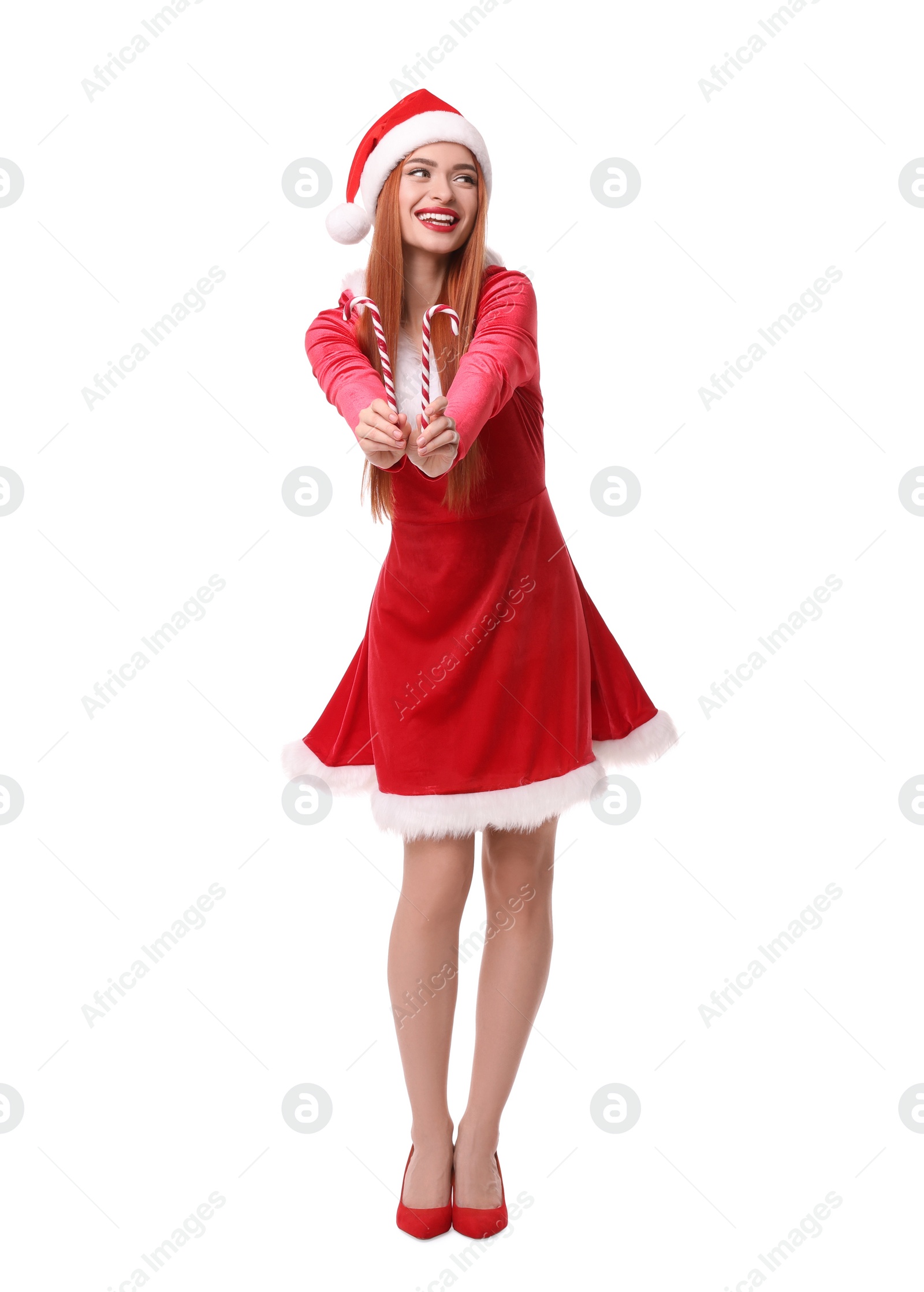 Photo of Young woman in red dress and Santa hat with candy canes on white background. Christmas celebration