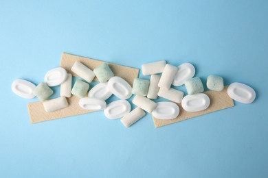 Photo of Many different chewing gums on light blue background, flat lay