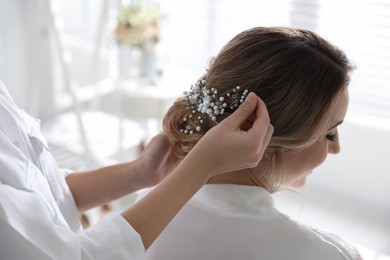 Photo of Professional stylist making wedding hairstyle for bride in salon