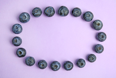 Frame of fresh ripe blueberries on lilac background, flat lay. Space for text