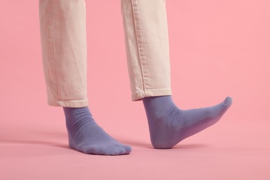 Photo of Woman in stylish purple socks and pants on pink background, closeup