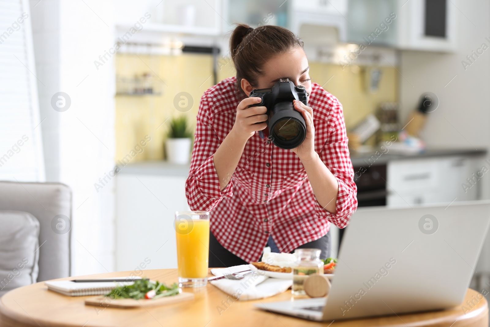 Photo of Food blogger taking photo of her lunch at wooden table indoors