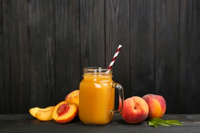 Photo of Natural peach juice and fresh fruits on black wooden table
