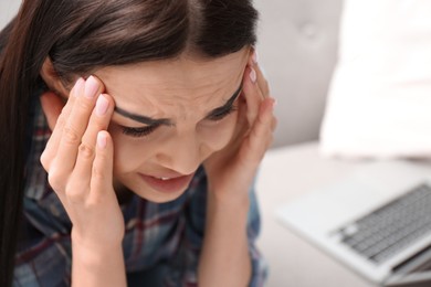 Photo of Young woman suffering from migraine at home, closeup. Space for text