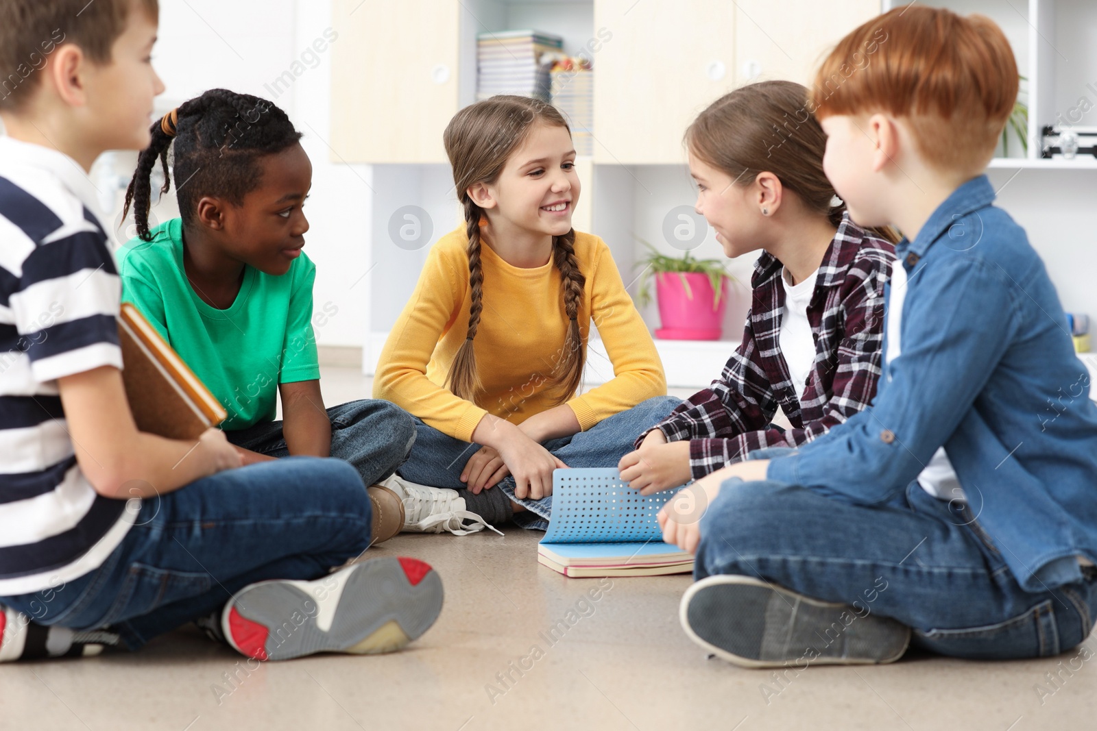 Photo of Cute children discussing in classroom at school