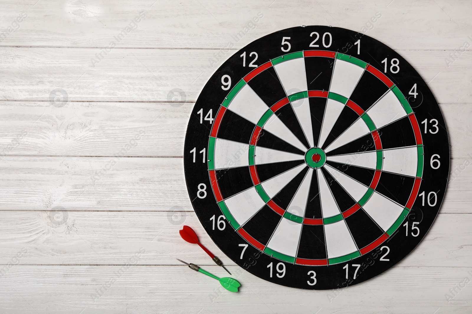 Photo of Dart board with color arrows on white wooden background, top view. Space for text