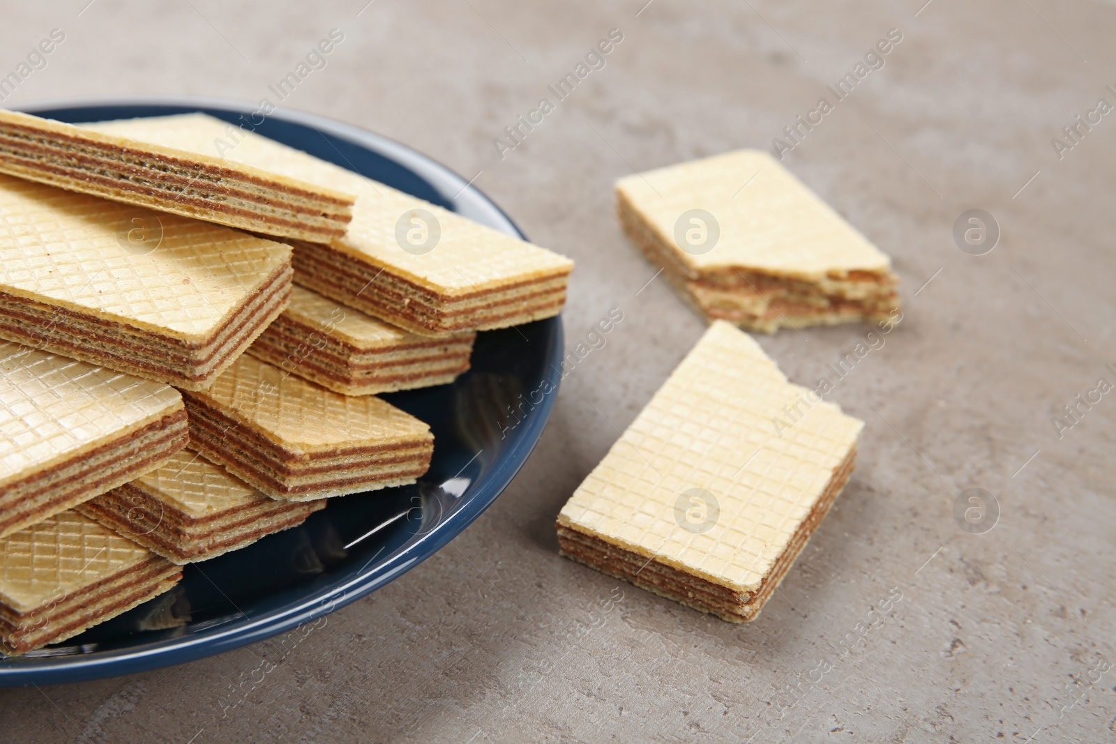 Photo of Plate of delicious wafers on grey stone background