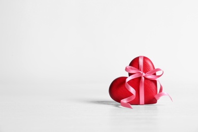 Red decorative heart with ribbon and bow knot on table. Space for text