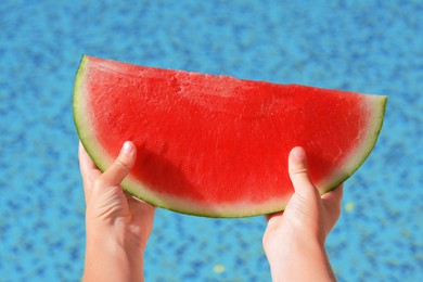 Photo of Child holding fresh juicy watermelon near swimming pool outdoors, closeup