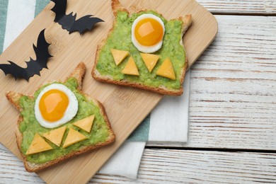 Photo of Halloween themed breakfast served on white wooden table, flat lay. Tasty sandwiches with fried eggs