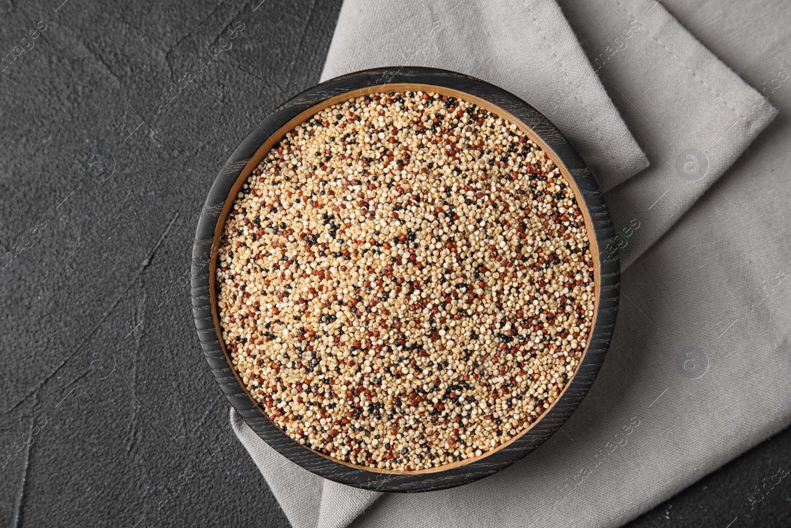 Photo of Plate with mixed quinoa seeds on dark background, top view